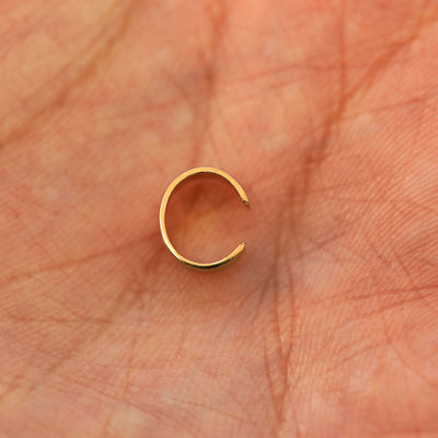 A solid yellow gold Thick Stardust Cuff earring resting in a model's palm to show the thickness of the cuff