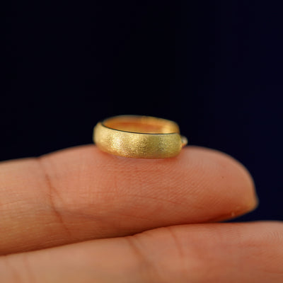 A solid yellow gold Thick Stardust Cuff earring resting on a model's fingertips