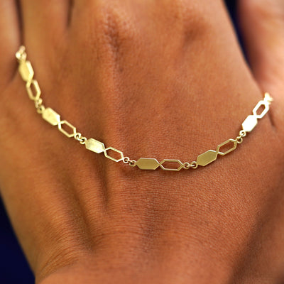 A solid gold Tanlah Chain resting on the back of a model's hand