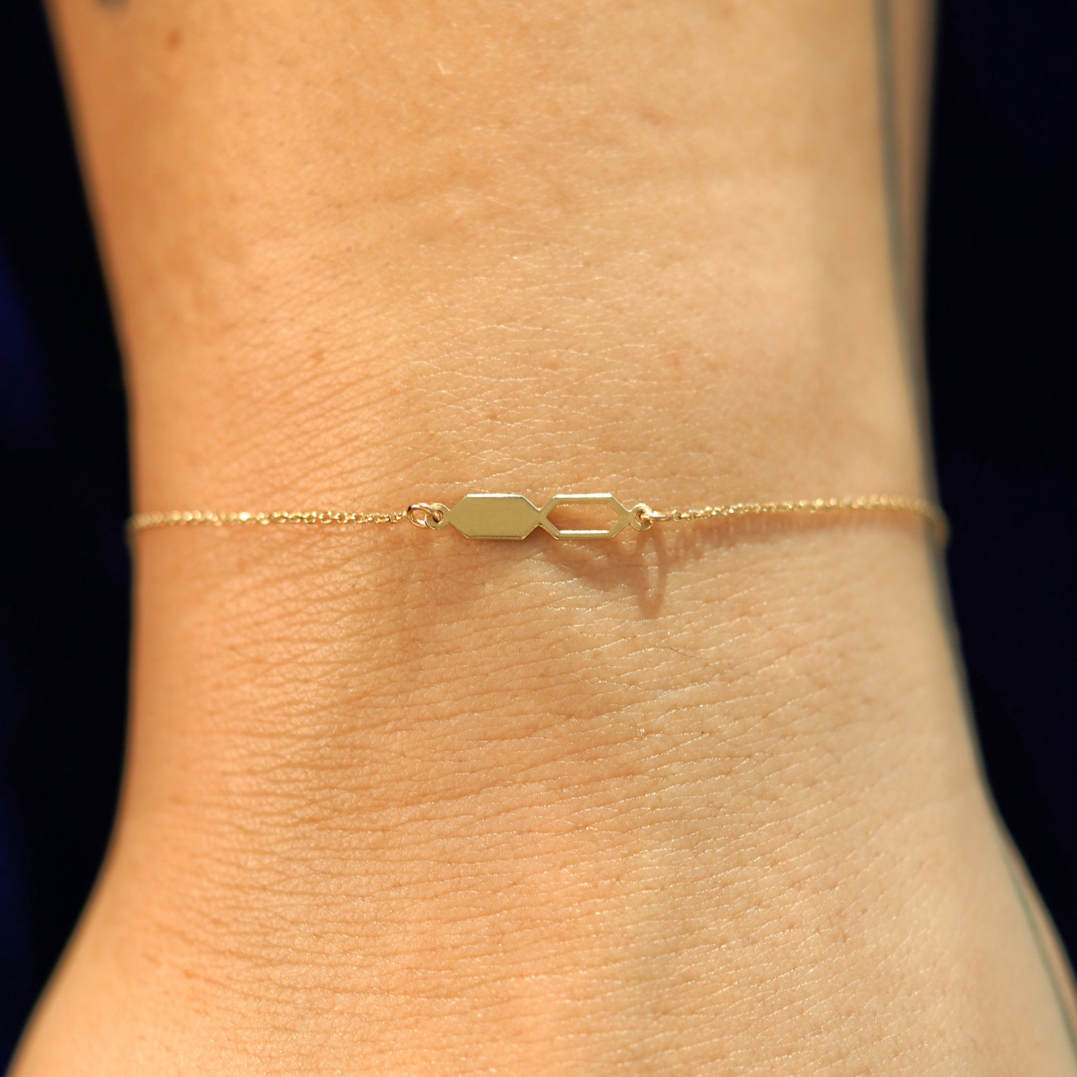 A model's wrist wearing a 14k yellow gold Tanlah Cable Bracelet
