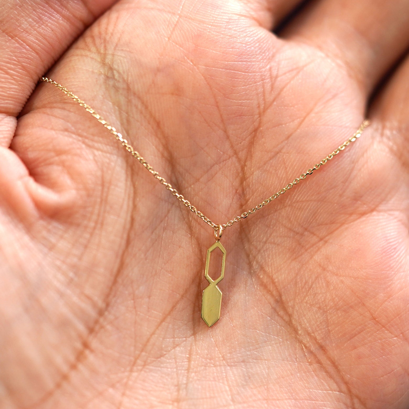 A yellow gold Tanlah Cable Necklace draped on a model's palm