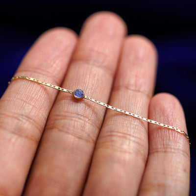 A yellow gold Tanzanite Bracelet resting on a model's fingers