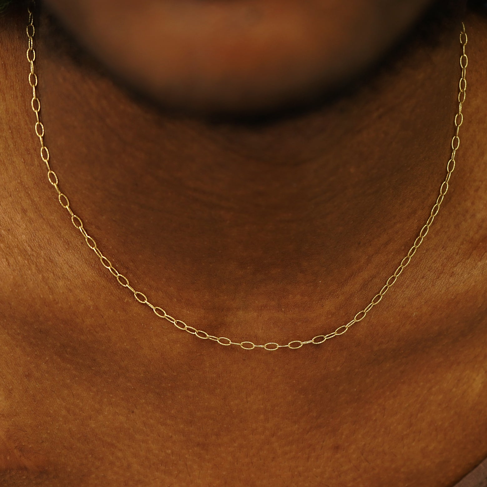A model's neck wearing a solid yellow gold Veren Chain