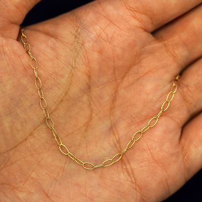 A yellow gold Veren Chain draped on a model's palm