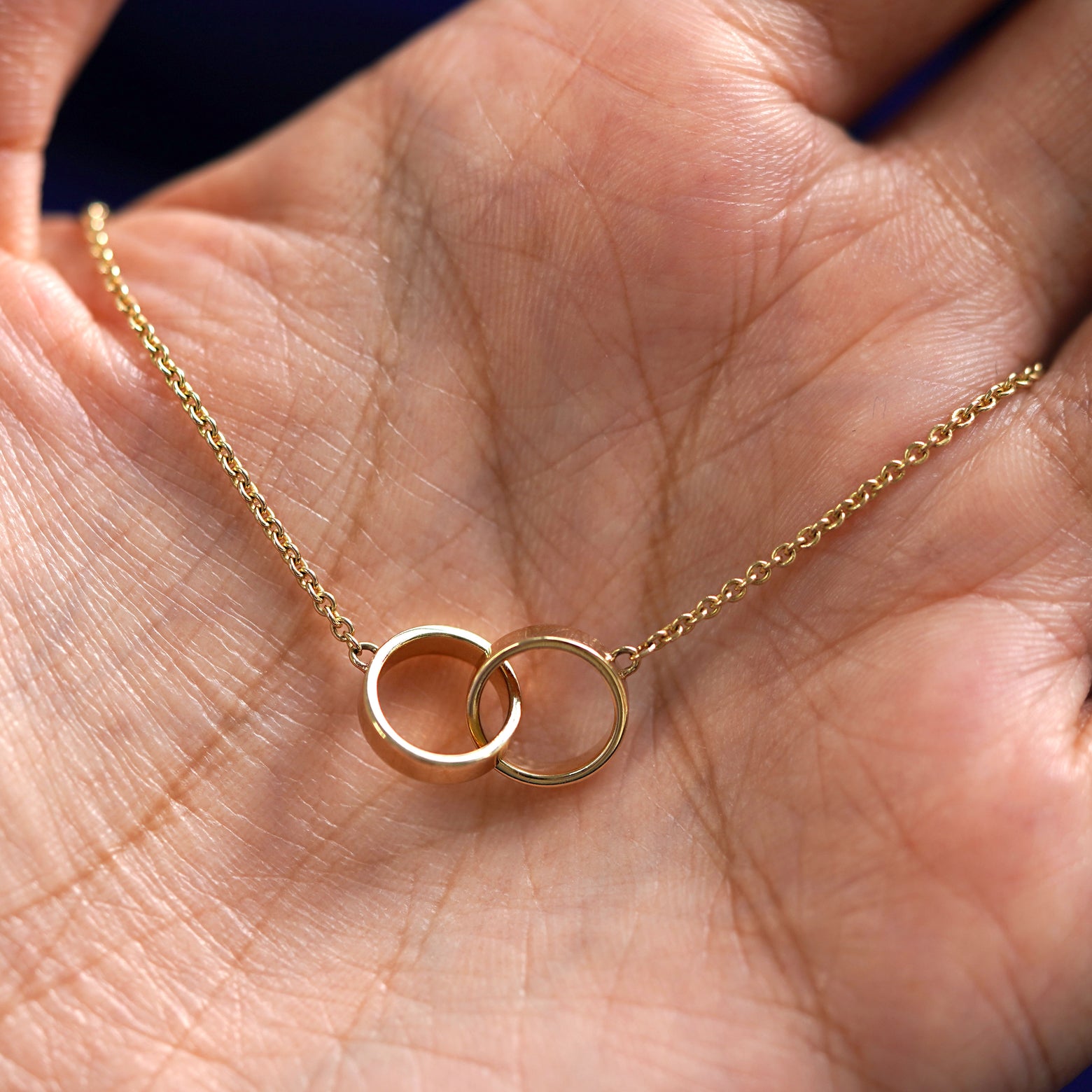 A yellow gold Bound Together Bracelet draped on a model's palm