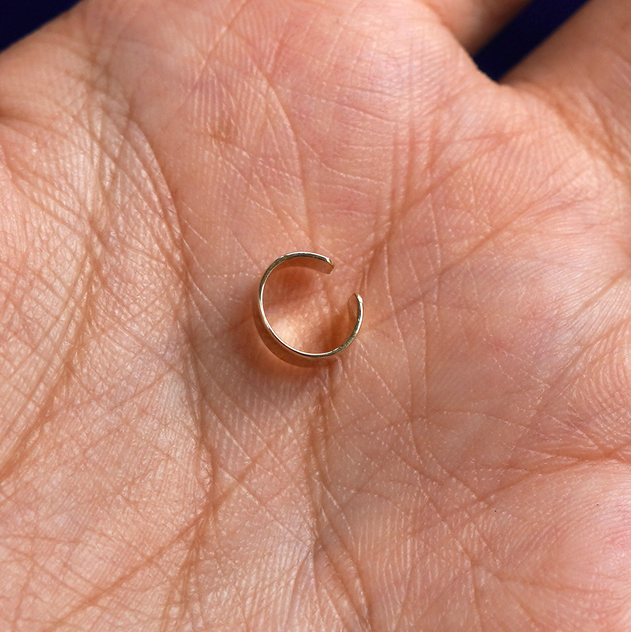 Alternate view of a solid yellow gold Thick Cuff earring resting in a model's palm