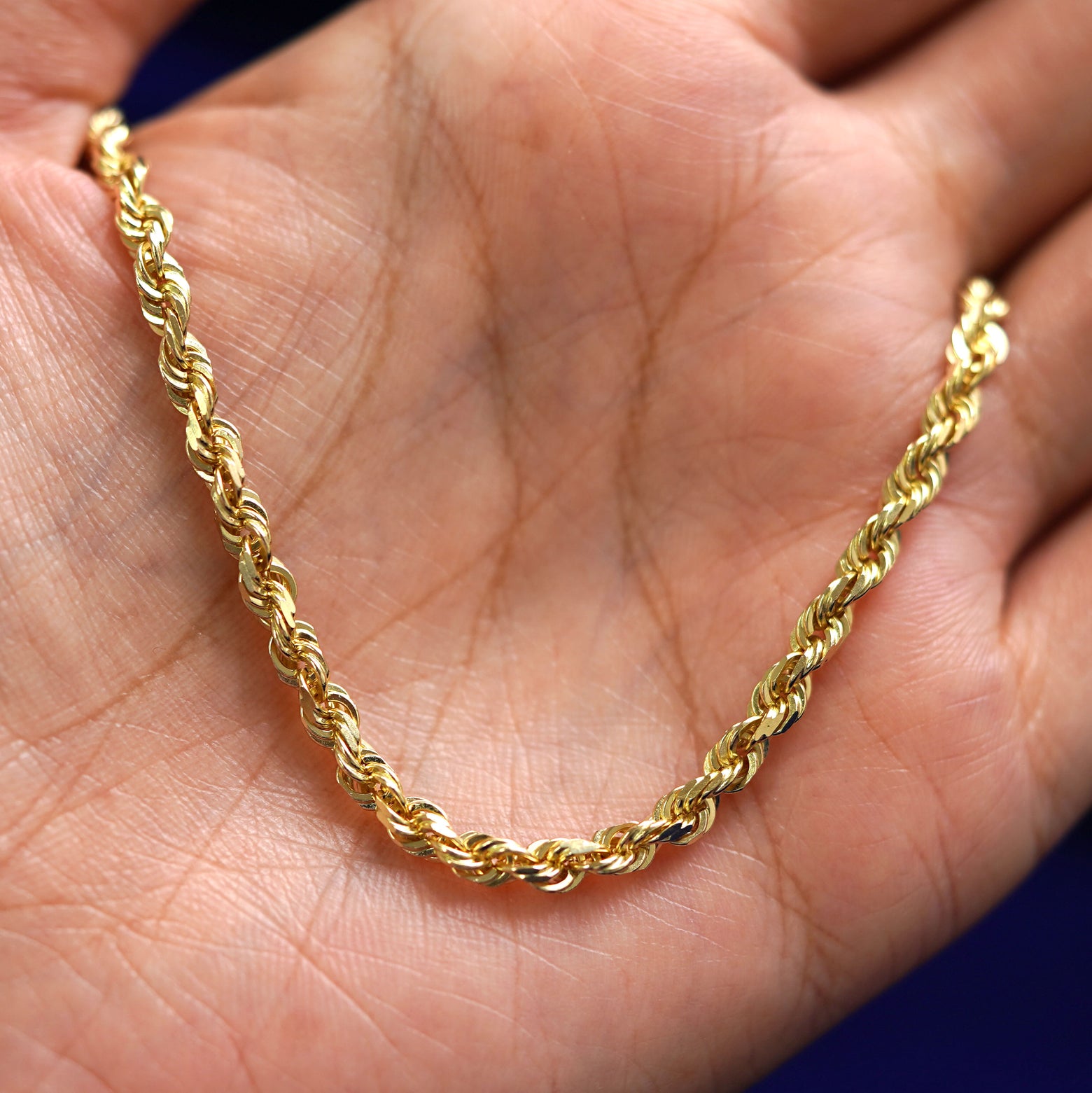 A yellow gold Thick Rope Bracelet draped on a model's palm