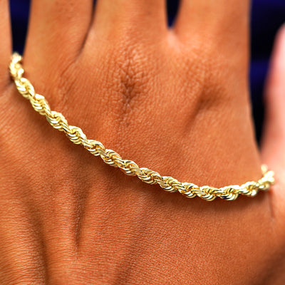 A solid gold Thick Rope Chain Bracelet resting on the back of a model's hand