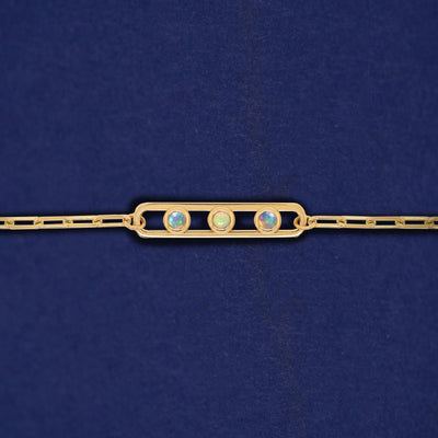 A yellow gold elongated open oval link with three bezel set Opals inside on a 14k gold Butch chain bracelet