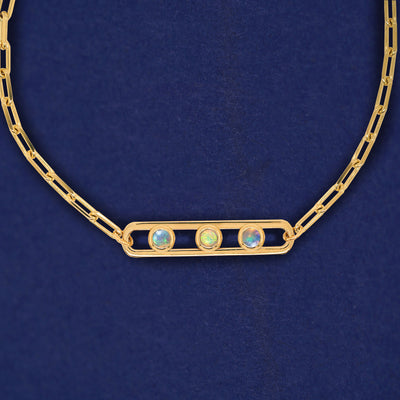 A yellow gold elongated open oval link with three bezel set Opals inside on a 14k gold Butch chain necklace