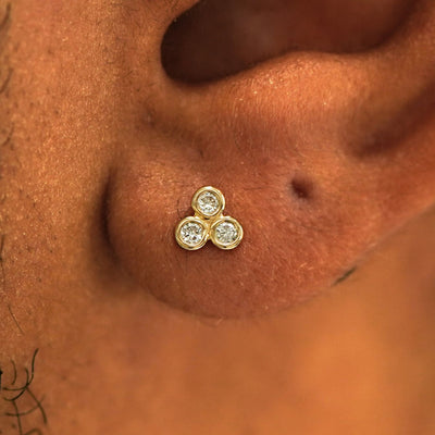 Close up view of a model's ear wearing a 14k yellow gold Diamond Trio Earring