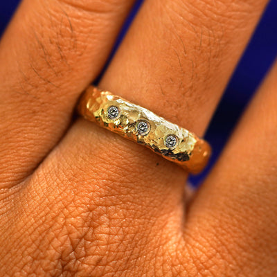 Close up view of a model's fingers wearing a 14k yellow gold Organic Band with three diamond