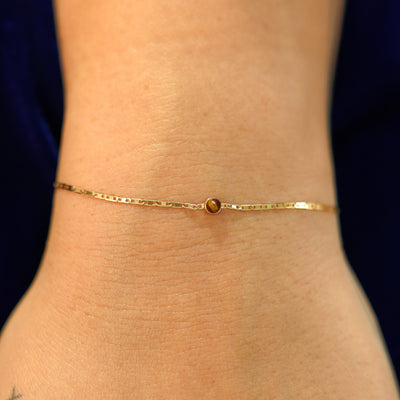 A model's wrist wearing a solid 14k yellow gold Tiger Eye Bracelet