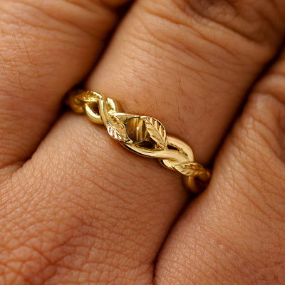 A solid 14k yellow gold tiger eye leaves and vines ring on a model's finger