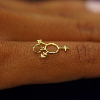 A 14k solid gold Trans Symbol Charm for chain balancing on the back of a model's finger