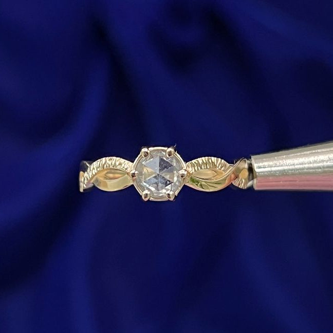 This 14k yellow gold band features a prongs-set rose-cut round salt and pepper diamond on a twisted-loop band with wooden-like texture