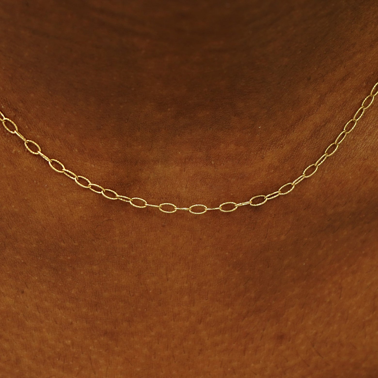 Close up view of a model's neck wearing a solid yellow gold Veren Chain