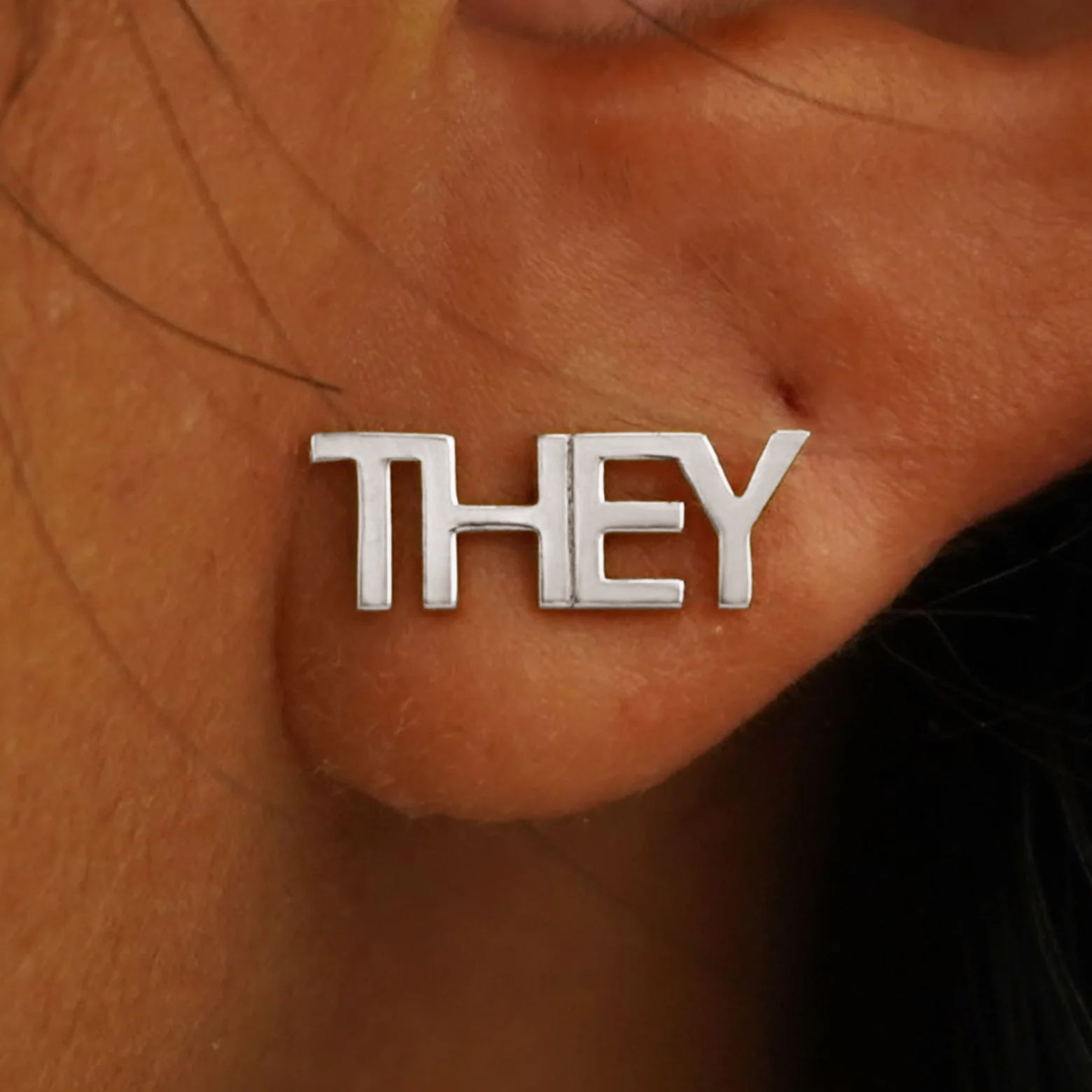 Close up view of a model's ear wearing a solid white gold They Earring