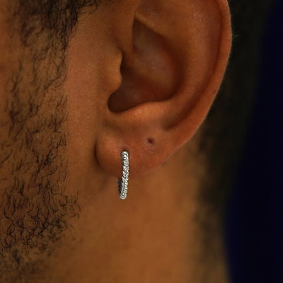 Close up view of a model's ear wearing a 14k white gold Medium Rope Huggie Hoop Earring