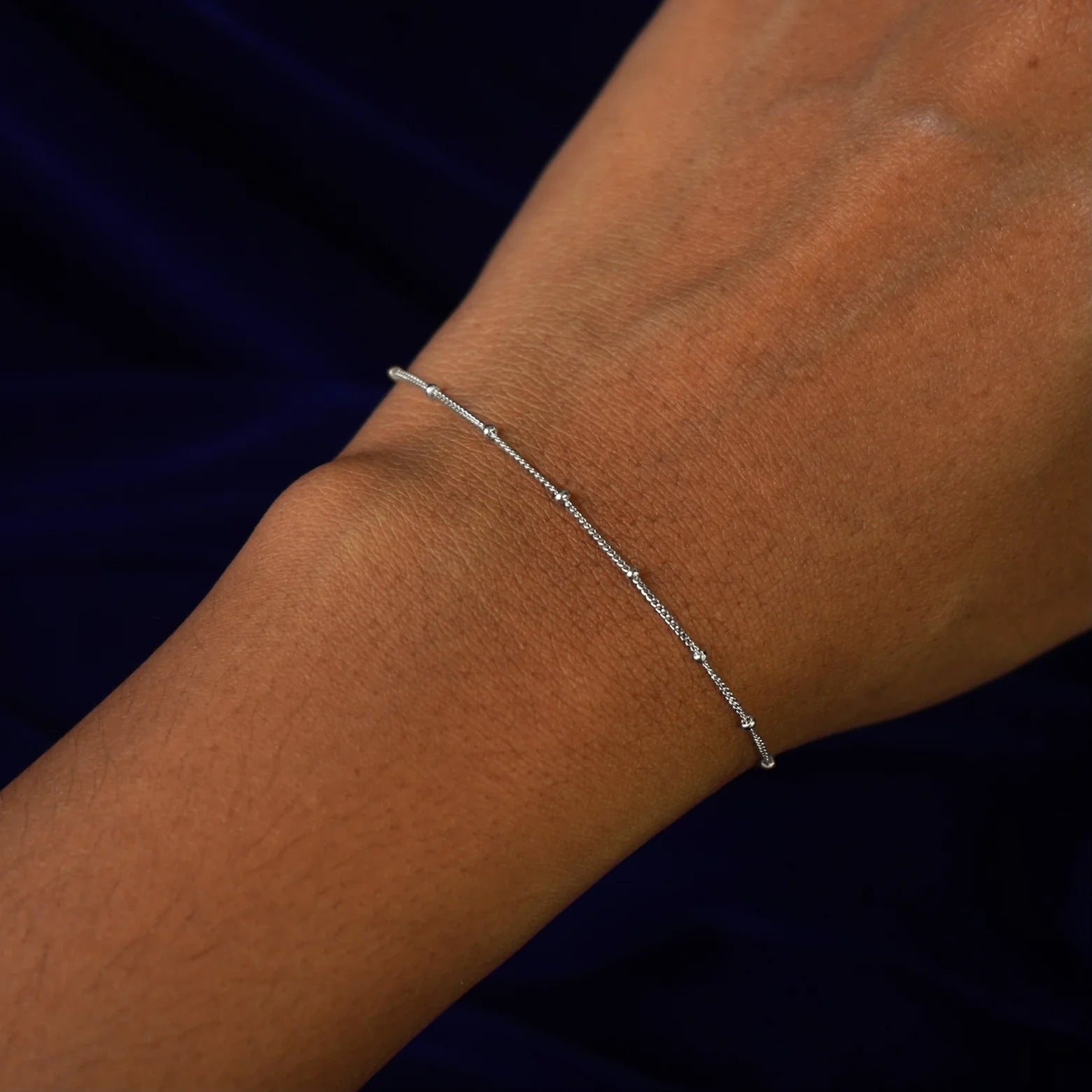 Close up view of a model's wrist wearing a white gold Beads Bracelet