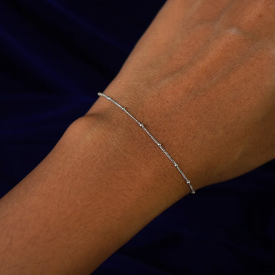 Close up view of a model's wrist wearing a white gold Beads Bracelet