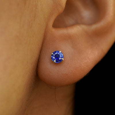 A model's ear wearing a solid 14k white gold blue sapphire pressure lock stud earring