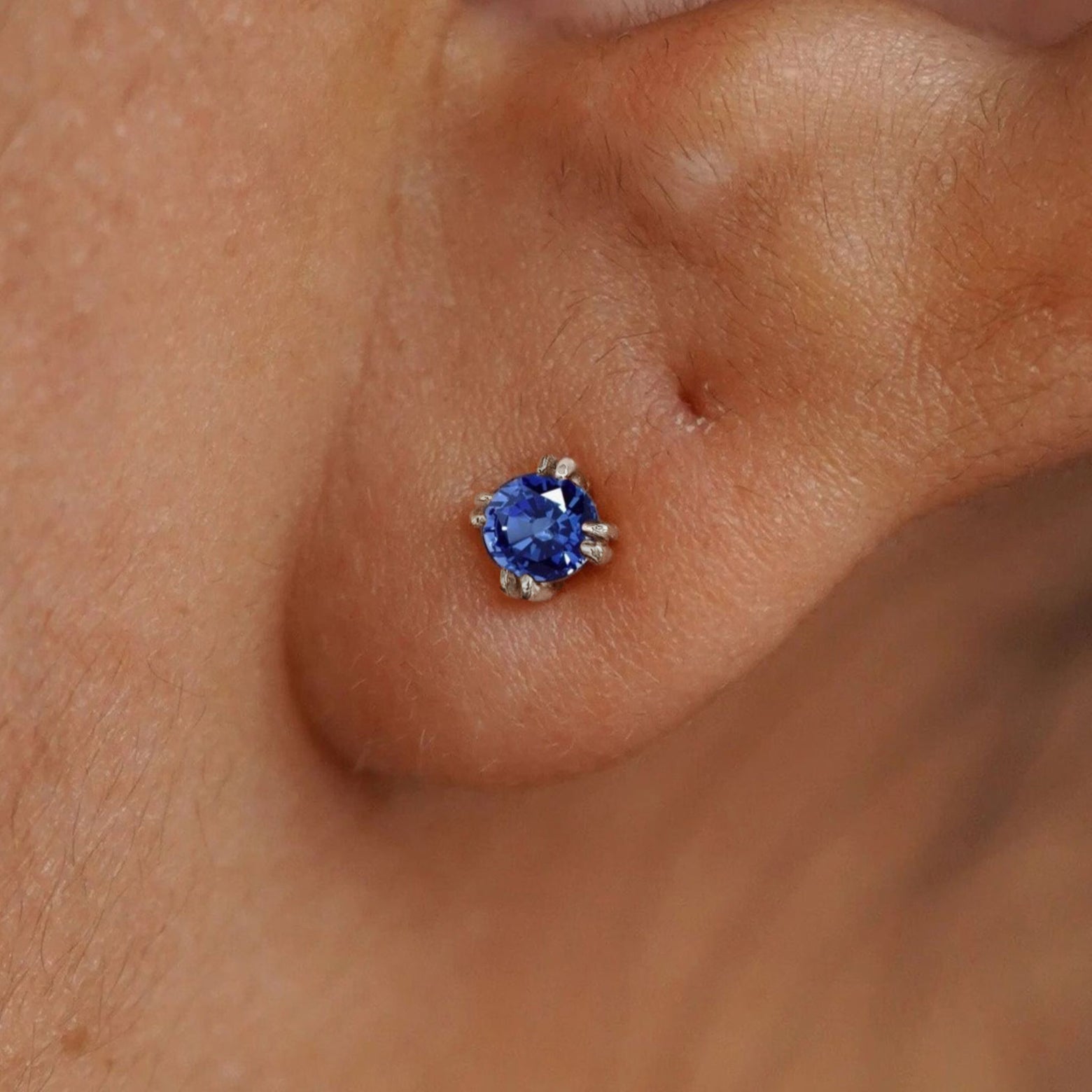 Close up view of a model's ear wearing a 14k white gold Sapphire Earring
