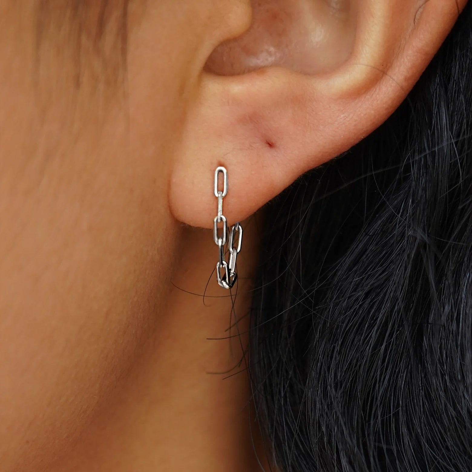 A model's ear wearing a white gold Butch Chain Loop Earring
