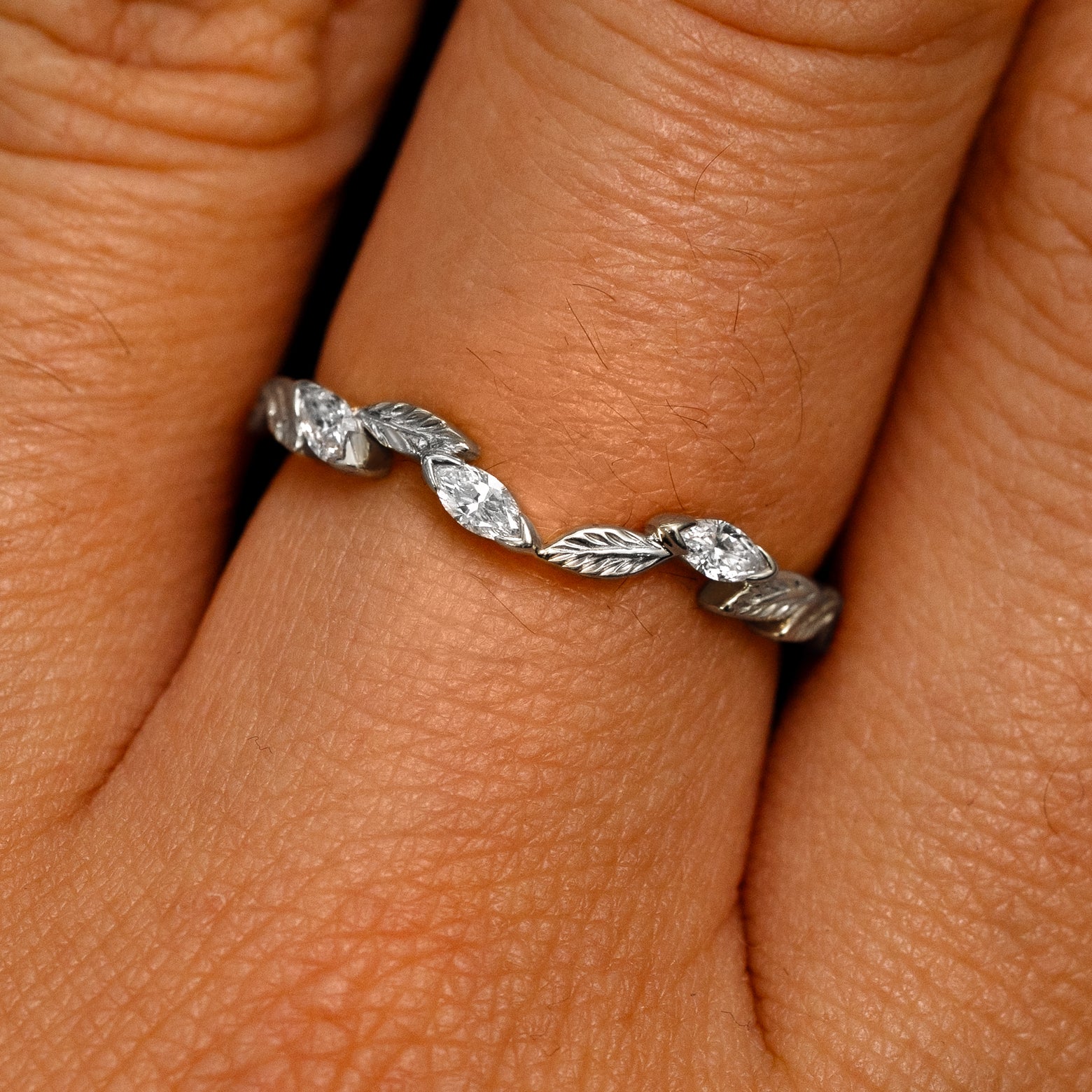 Close up view of a model's fingers wearing a 14k white gold Chevron Leaves and Marquise Diamonds Band