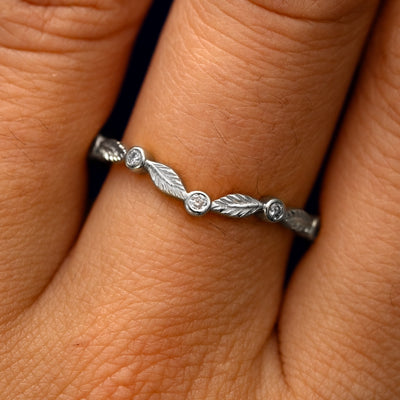 Close up view of a model's fingers wearing a 14k white gold Chevron Leaves and Round Diamonds Band