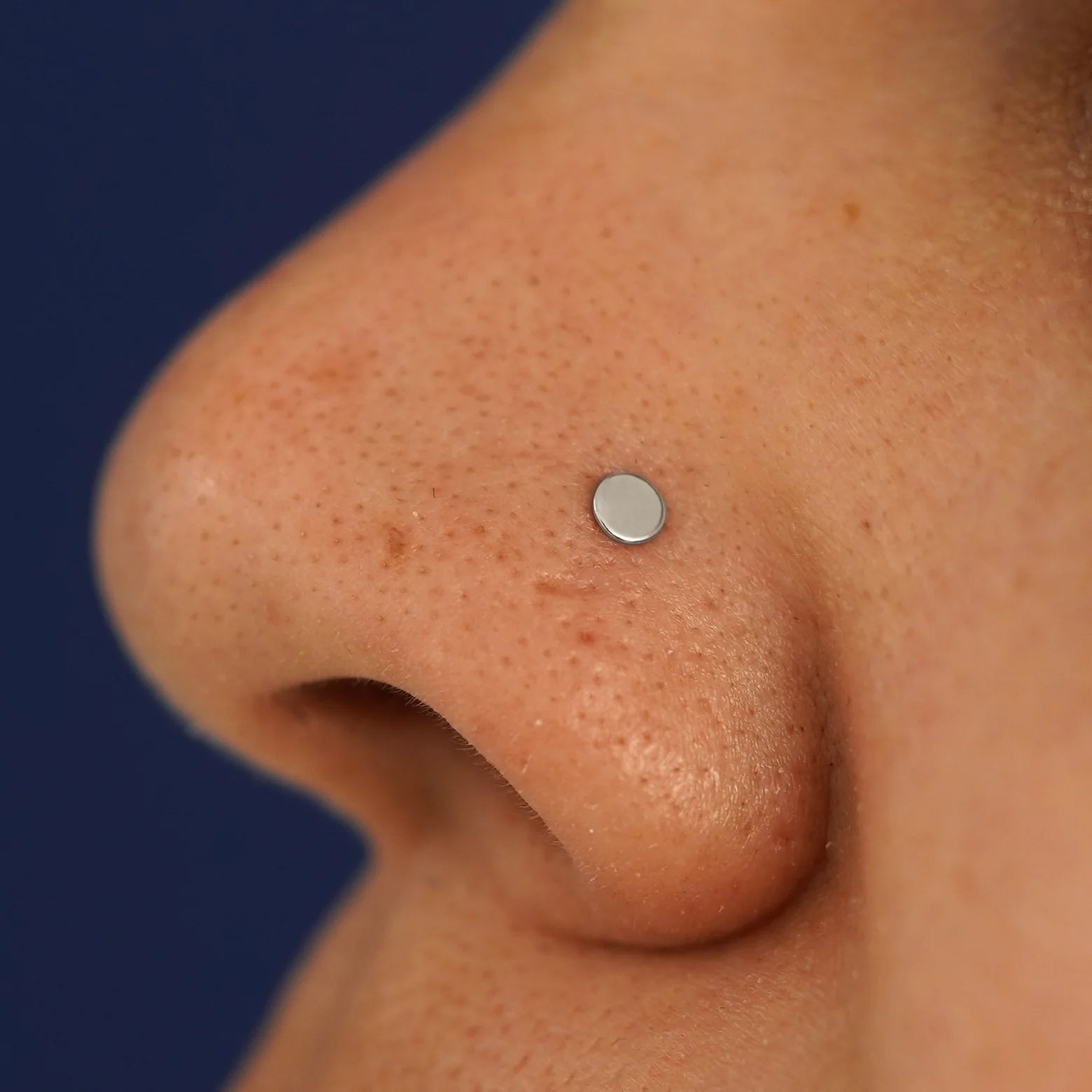 Close up view of a model's nose wearing a white gold Circle Nose Stud