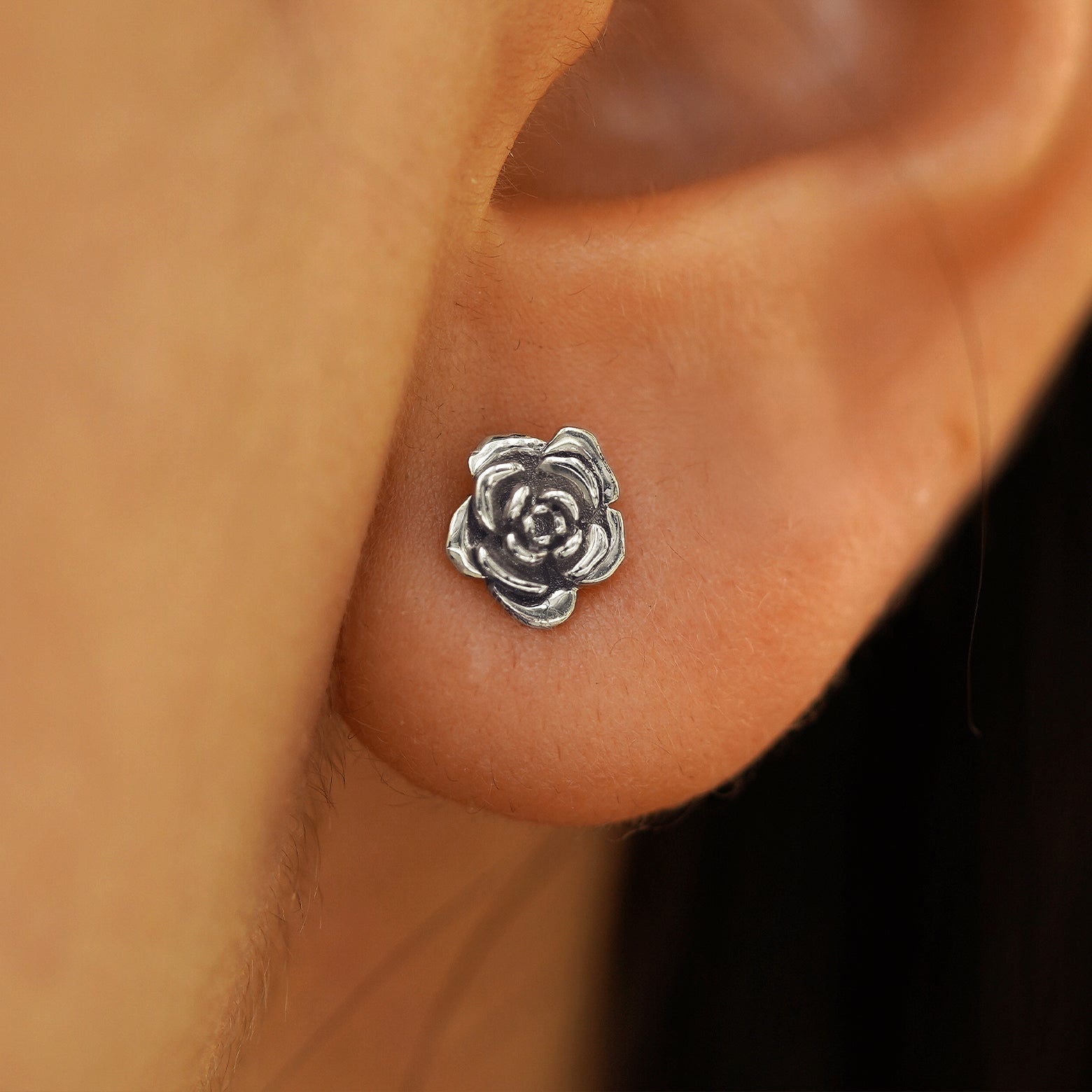 Close up view of a model's ear wearing a 14k white gold Rose Earring