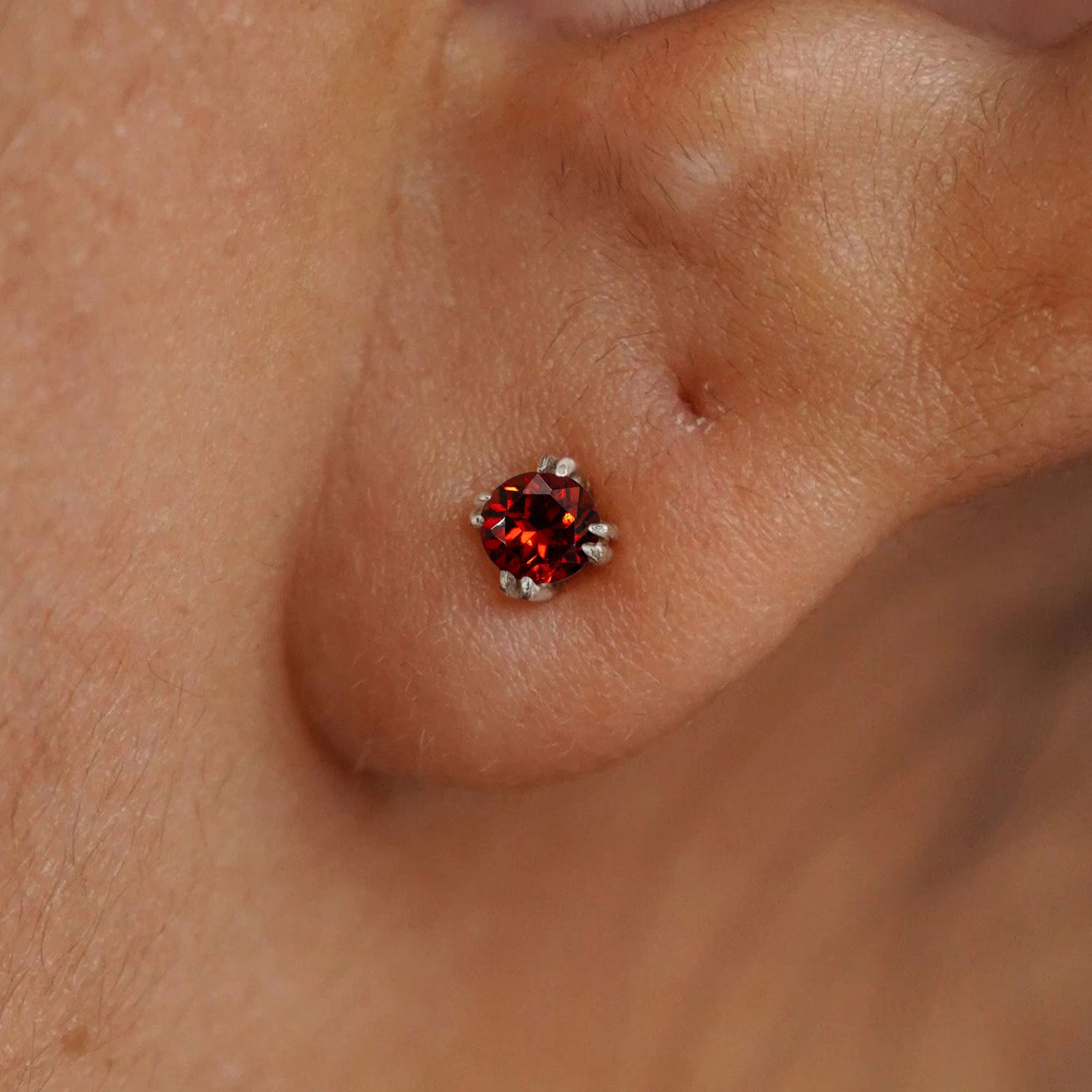 Close up view of a model's ear wearing a 14k white gold Garnet Earring