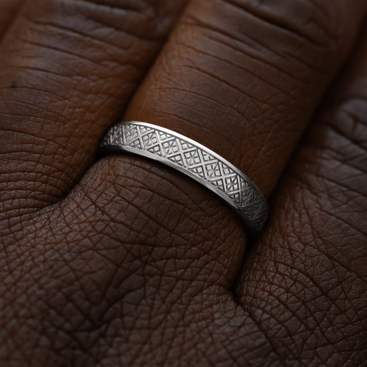 Close up view of a model wearing a solid 14k white gold diamond patterned band
