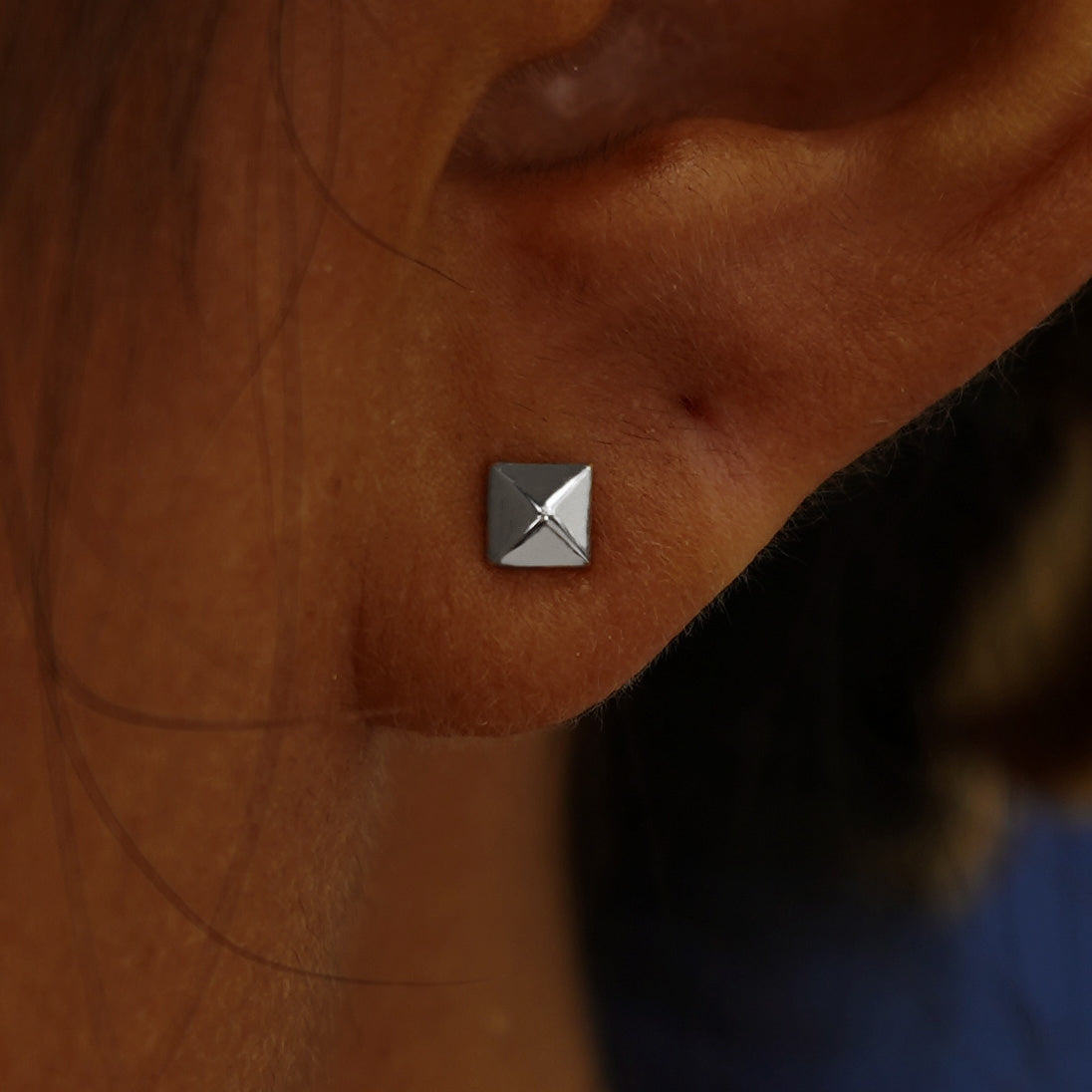 Close up view of a model's ear wearing a white gold Pyramid Earring