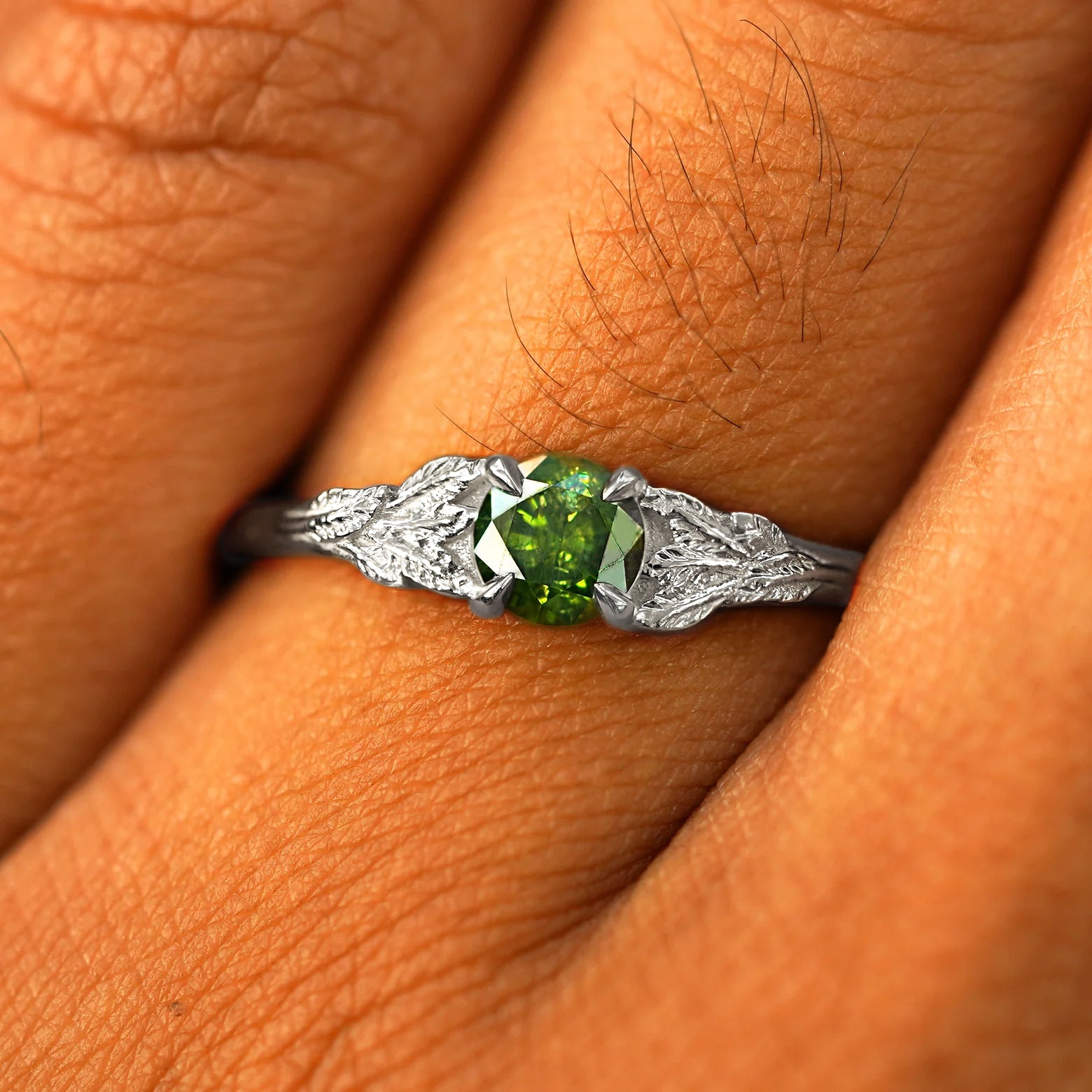 Close up view of a model's fingers wearing a 14k white gold Green Diamond Leaves Ring