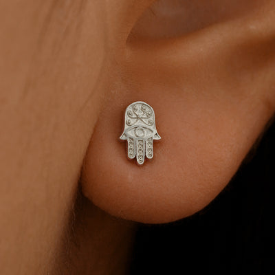 Close up view of a model's ear wearing a 14k white gold Hamsa Earring