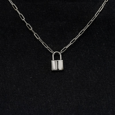 Close up view of a solid 14k white gold lock necklace against a model's black shirt