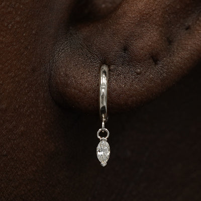 Close up view of a model's ear wearing a white gold Marquise Lab Diamond Dangle Huggie Hoop