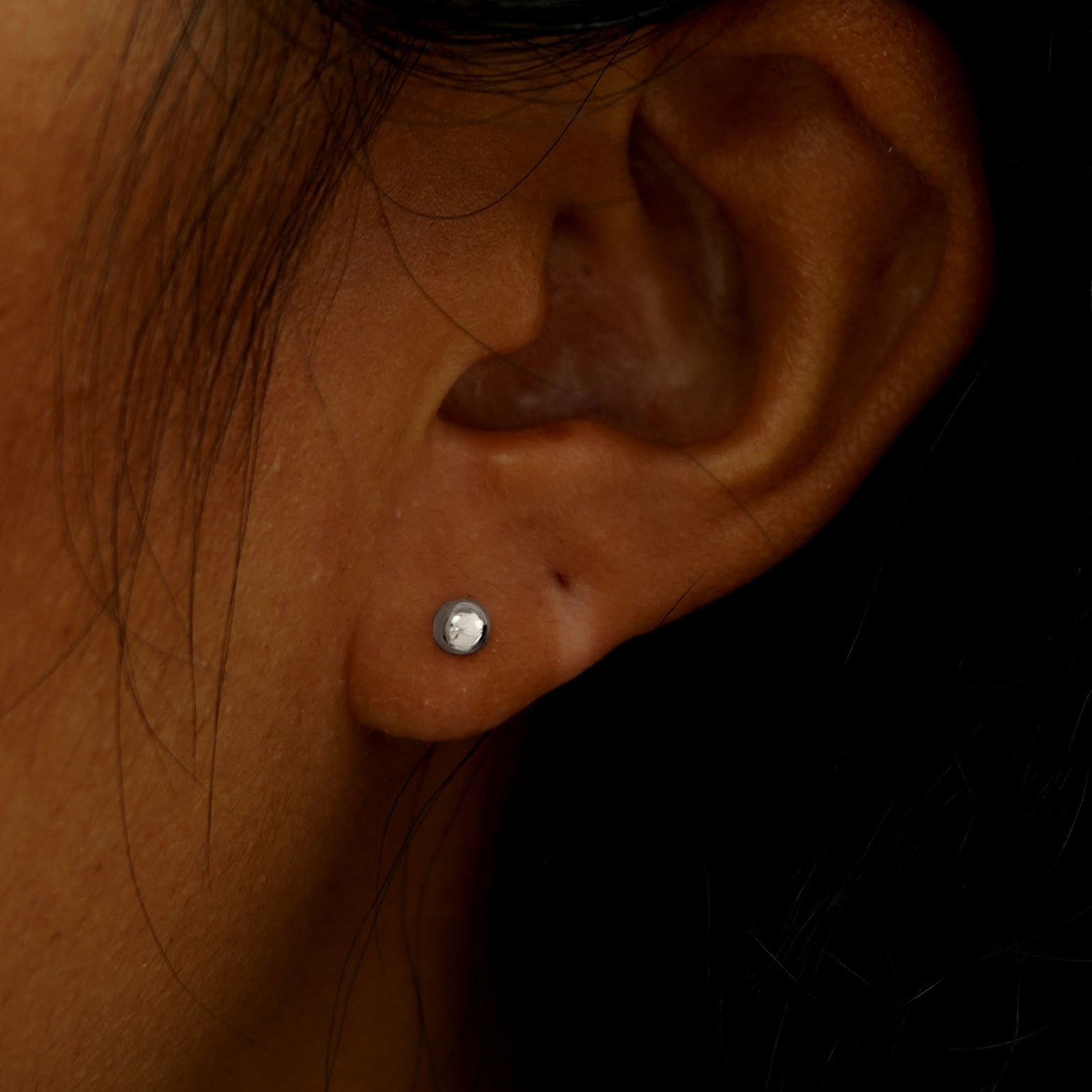 Close up view of a model's ear wearing a white gold Medium Ball Earring