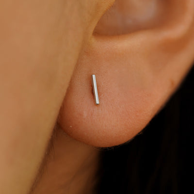 Close up of model's ear, they are wearing a white gold Medium Line Earring.
