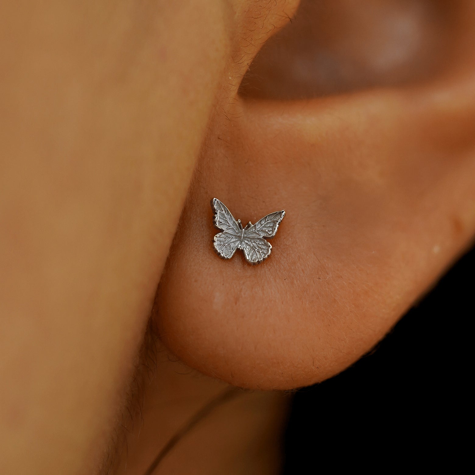 Close up view of a model's ear wearing a 14k white gold Mini Butterfly Earring
