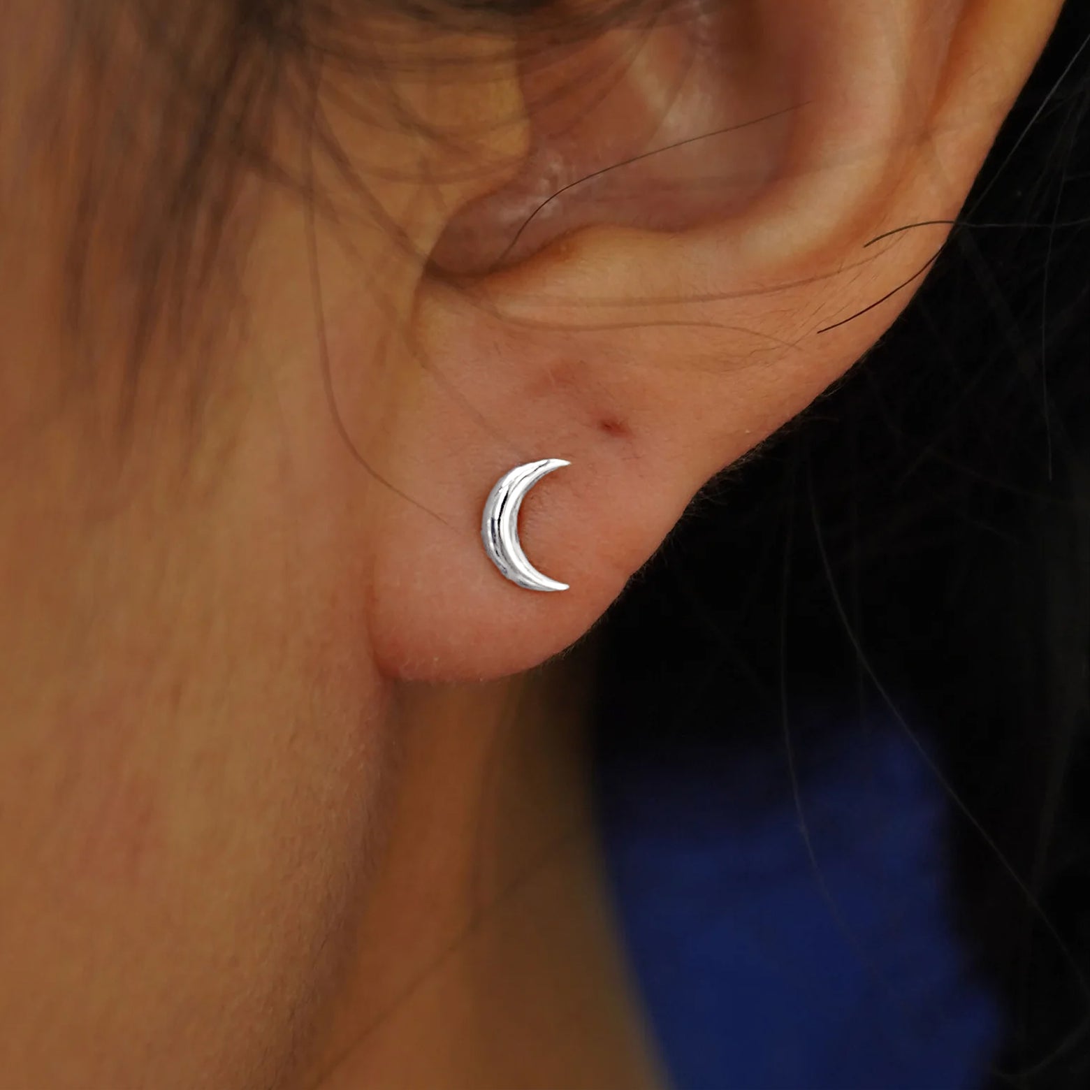Close up view of a model's ear wearing a white gold Moon Flat Back Earring