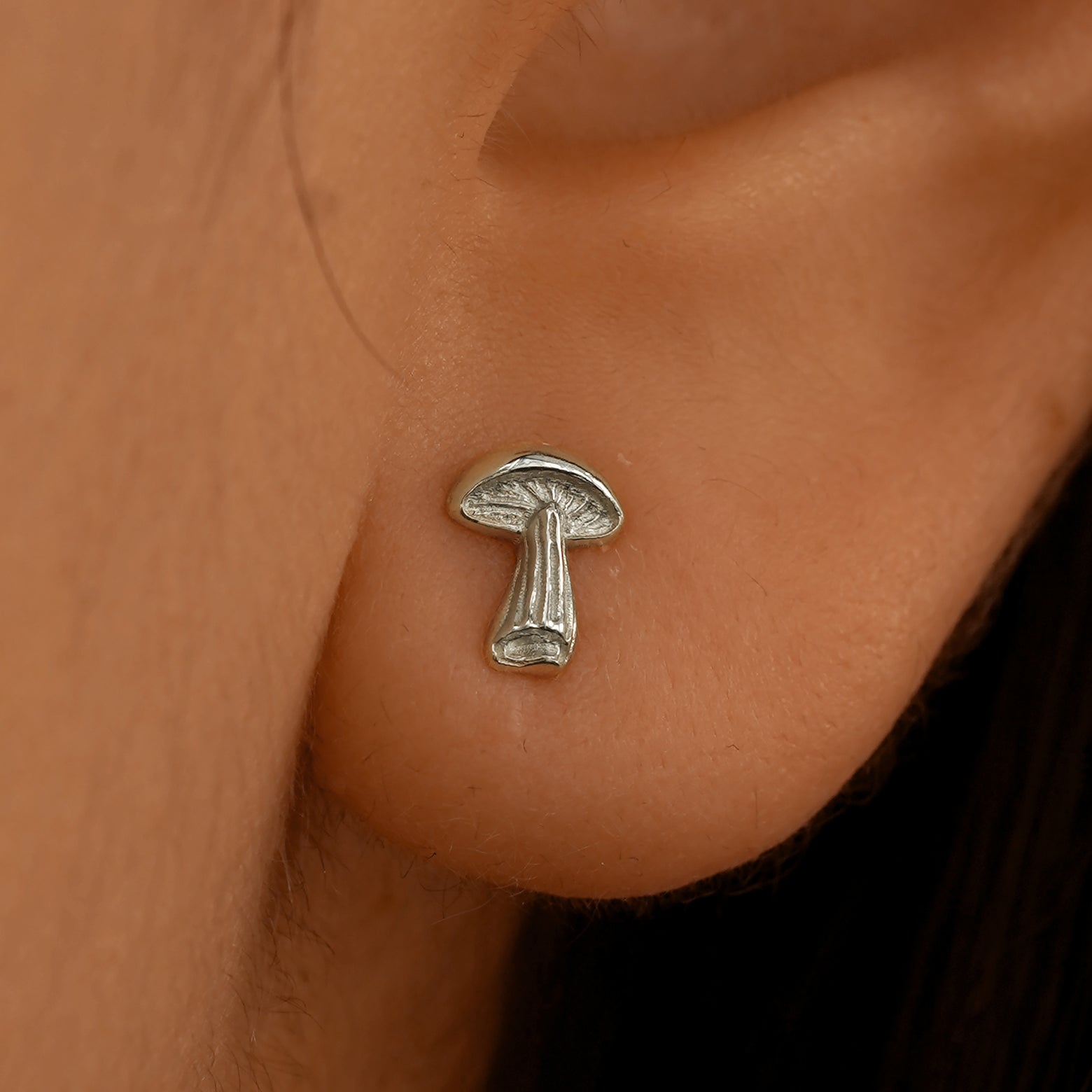 Close up view of a model's ear wearing a 14k white gold Mushroom Earring