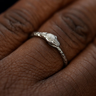 Close up view of a model's hand wearing a white gold Ouroboros Snake Ring