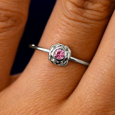 A solid 14k white gold Pink Sapphire Gemstone Flower Ring on a model's finger