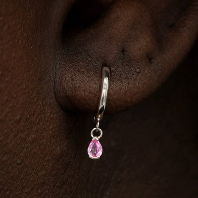 Close up view of a model's ear wearing a white gold Pink Sapphire Dangle Huggie Hoop