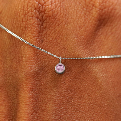 Close up view of a 14k white gold Pink Sapphire Necklace draped across the back of a model's hand