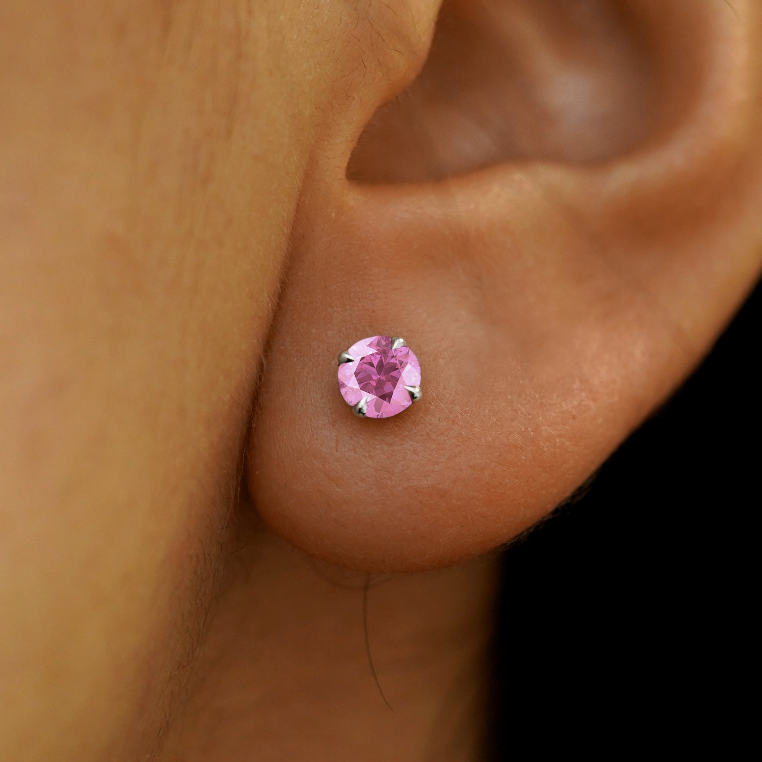 A model's ear wearing a solid white 14k gold pink sapphire pressure lock earring
