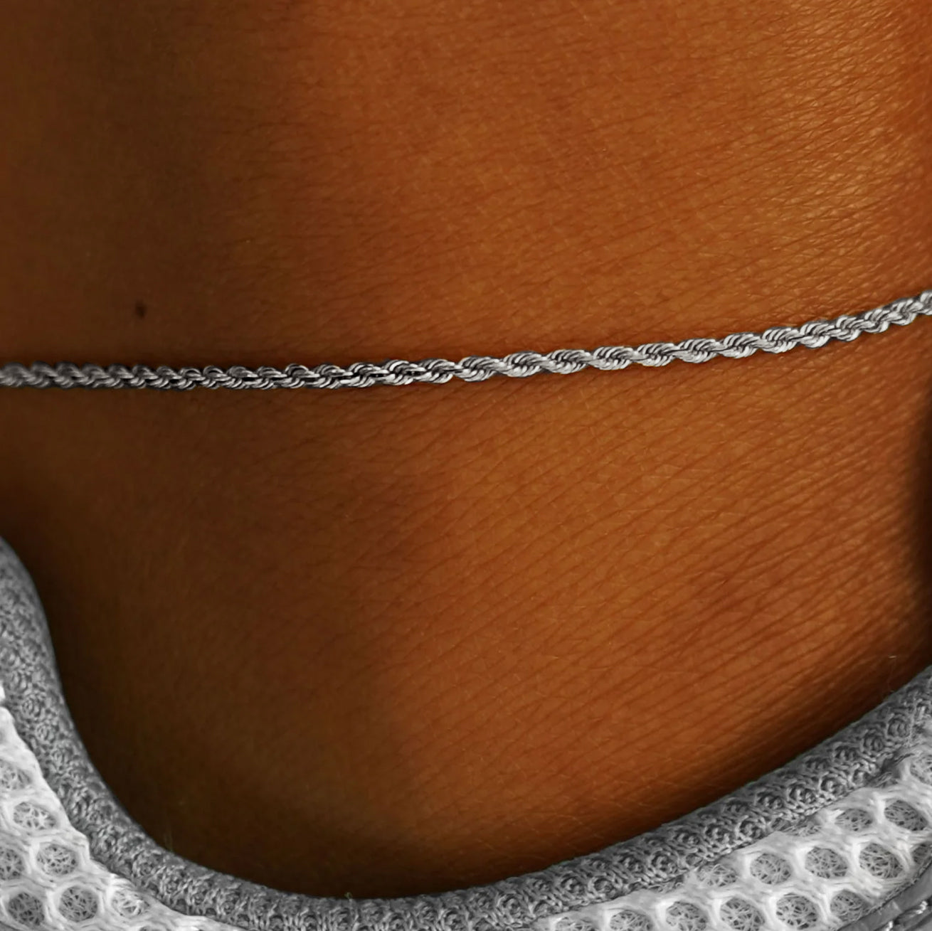 Close up view of a model's ankle wearing a white gold Rope Anklet